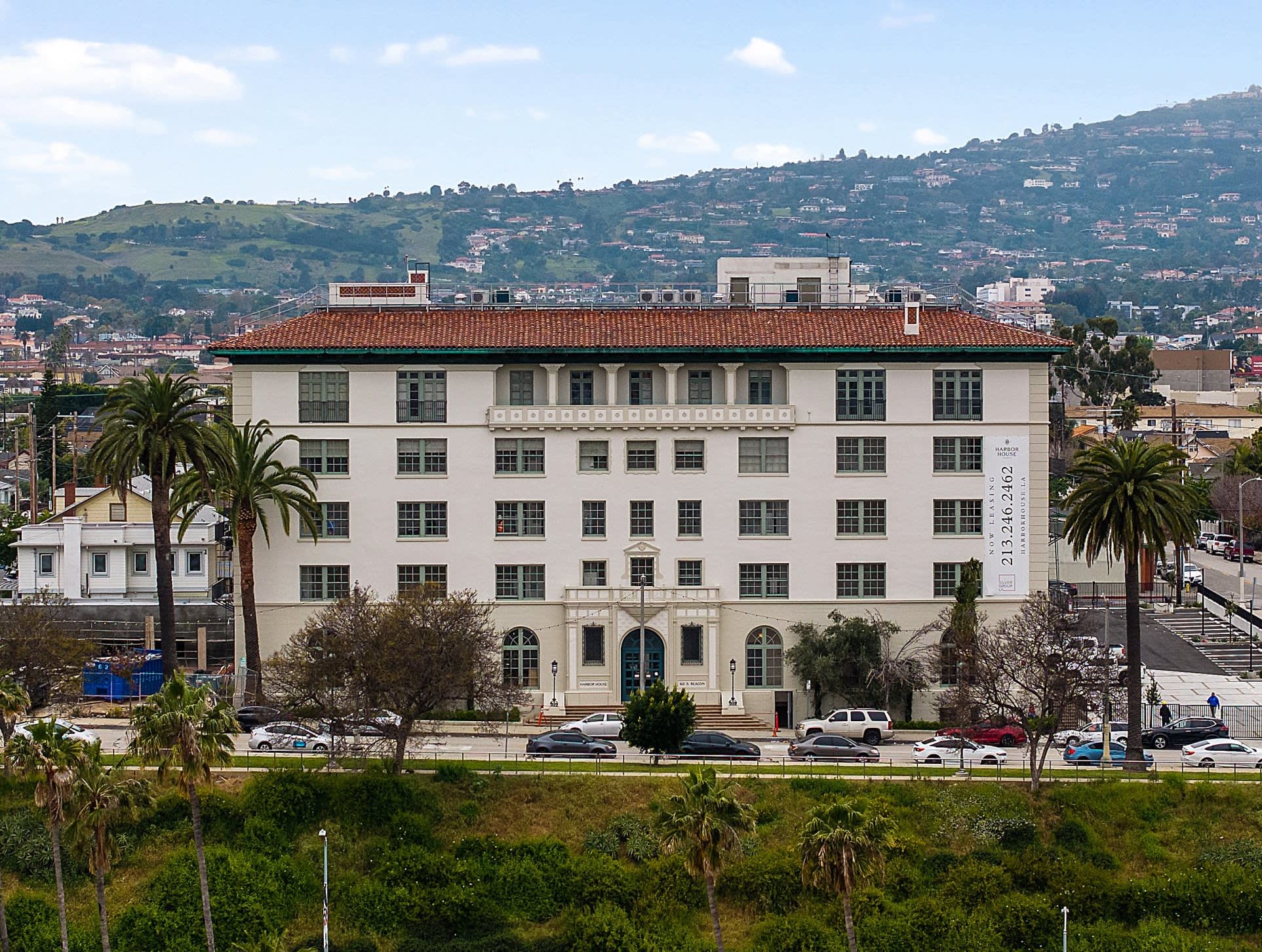 Located in between Downtown San Pedro and the Main Harbor Channel, the historic Harbor House has panoramic, water-front views of the Port of Los Angeles. This five-story Mediterranean Revival building was constructed in 1925, originally as an Army and Navy YMCA. 

Omgivning was tasked with the adaptive reuse of the 107,000 square-foot structure — comprising five stories and a basement — into a mixed-use building with residential units, a restaurant, lobby/lounge, basketball court, and a new pool. Work also included a seismic retrofit of the non-ductile concrete structure, as well as the installation of all new mechanical, electrical, and plumbing systems.
<br><br>
### History

Built to support the nearby Naval Base San Pedro, the original YMCA building was designed by Jay, Rogers & Stevenson Architects, who were responsible for popular structures across Los Angeles and San Diego in the early decades of the 20th century. It originally housed a gym, pool, coffee shop, cafeteria, dormitory with 410 beds, and open-air handball courts, which were enclosed in 1944.  In the 1940s, the building was converted from military to civilian use as a nursing home. The YMCA’s pool was filled in and a large portion of the ground floor became administration and back-of-house.

Harbor House was designated as a historic landmark in 1982 and even with this significant change of use, Omgivning met the Secretary of the Interior Standards for Rehabilitation and the Owner was able to obtain National historic tax credits. Throughout the building, the team preserved many of the original features, including painted beams in the grand lobby, tilework, artistic trim painting, and the existing basketball court with a running track above.  
