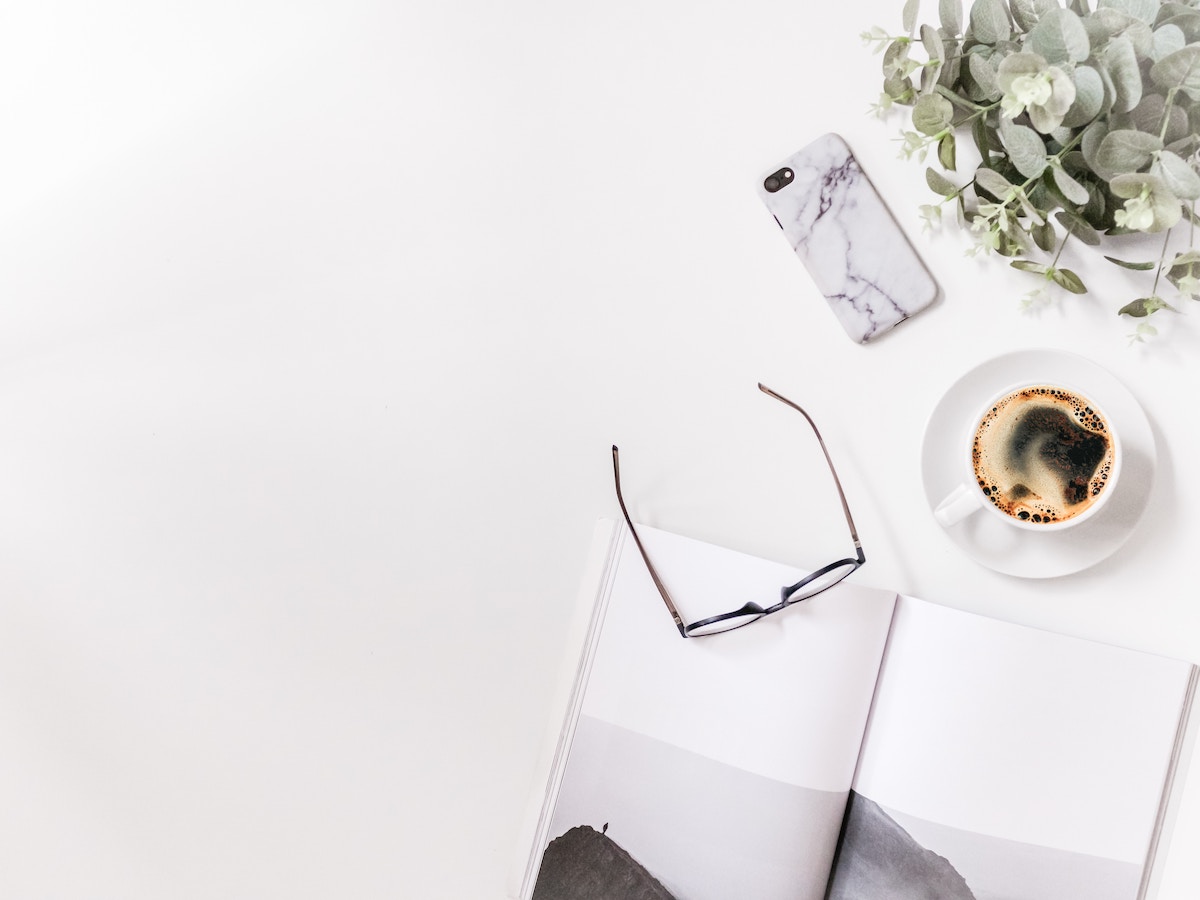 an open book with reading glasses and a cup of coffee nearby