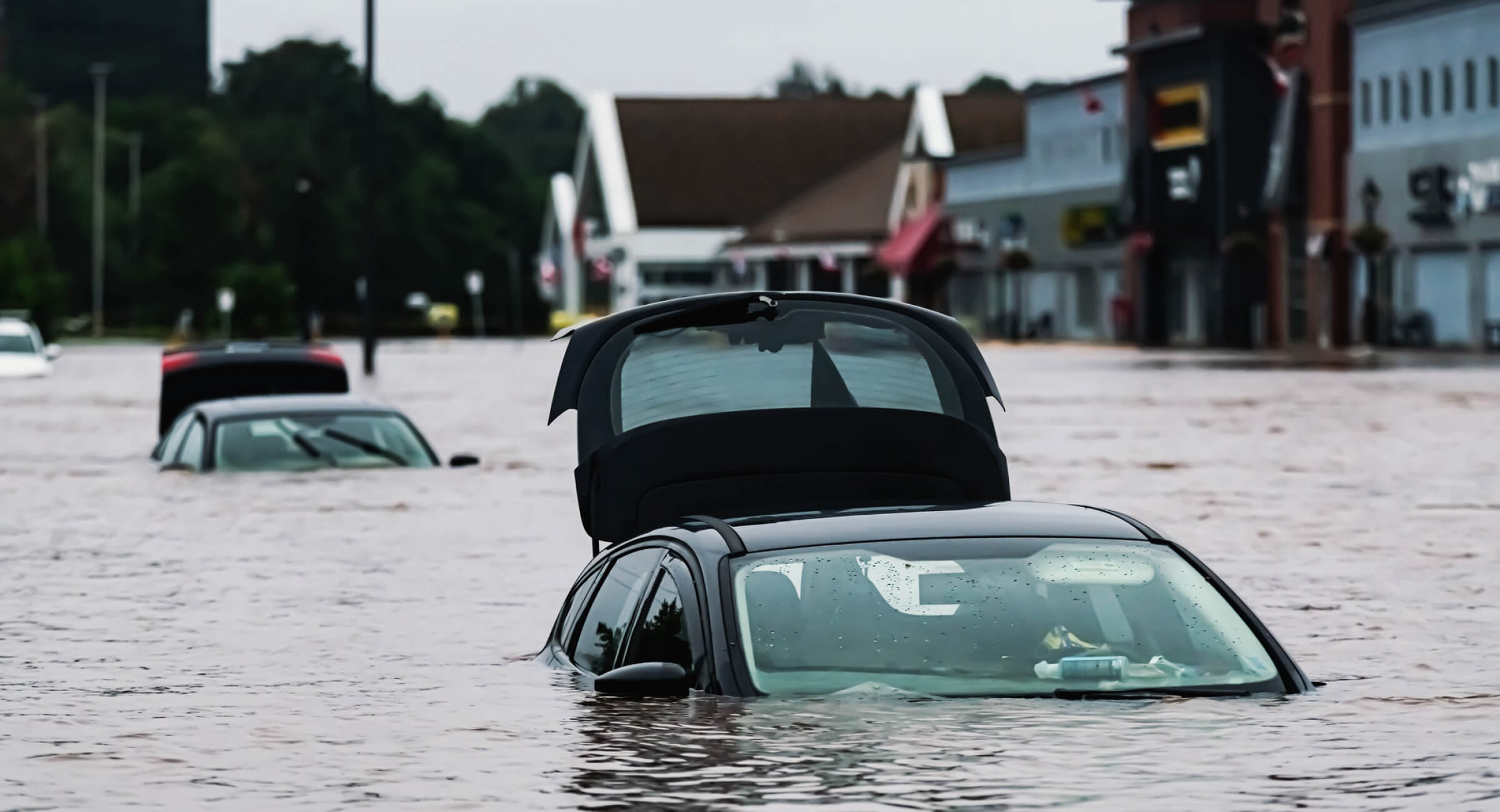 Two cars submerged in water on a flooded city street.