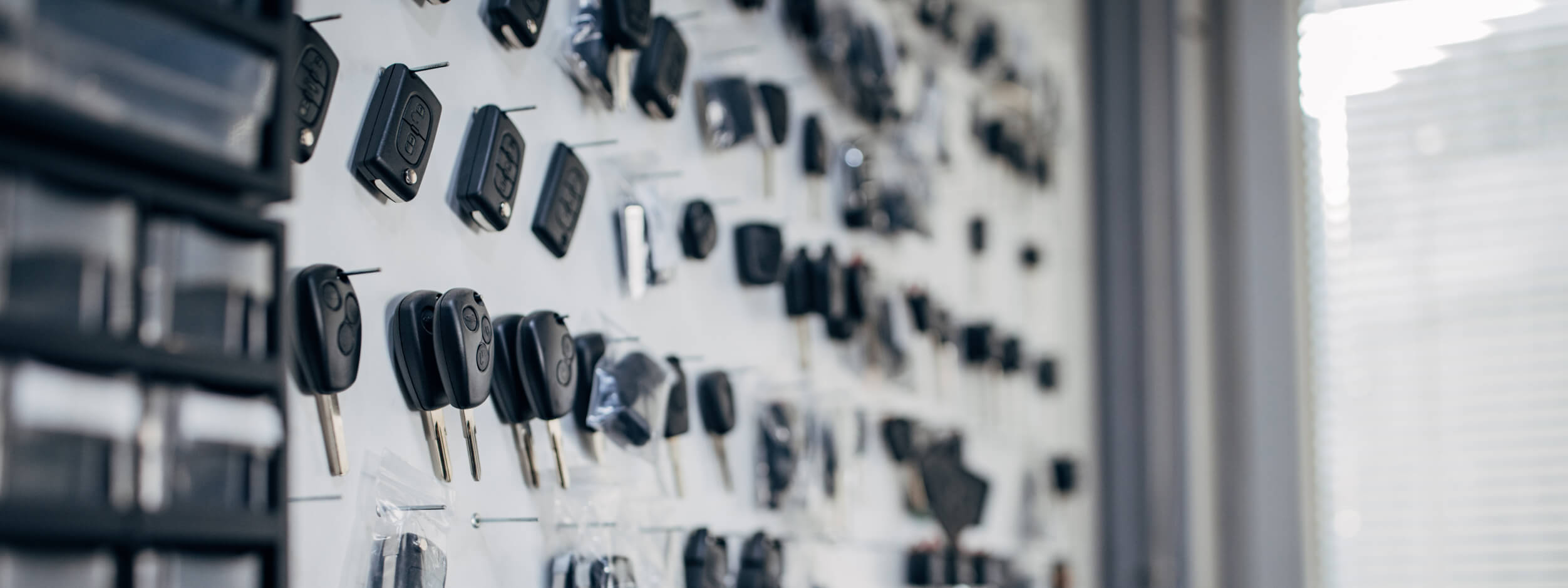 Dozens of different vehicle keys hanging on a wall.