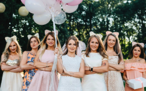 A group of hen party girls standing in a row holding balloons