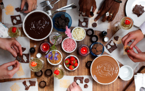 Many hands making chocolate treats on a table
