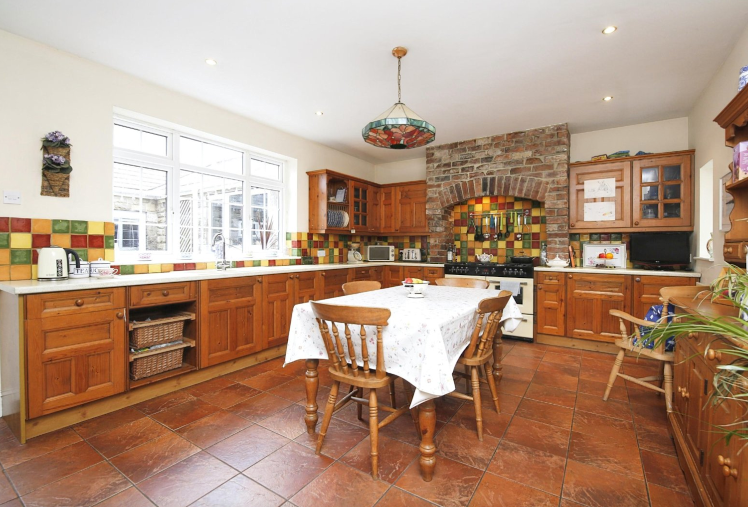 A country kitchen with terracotta tiles and an open brick oven area and wooden cabinets