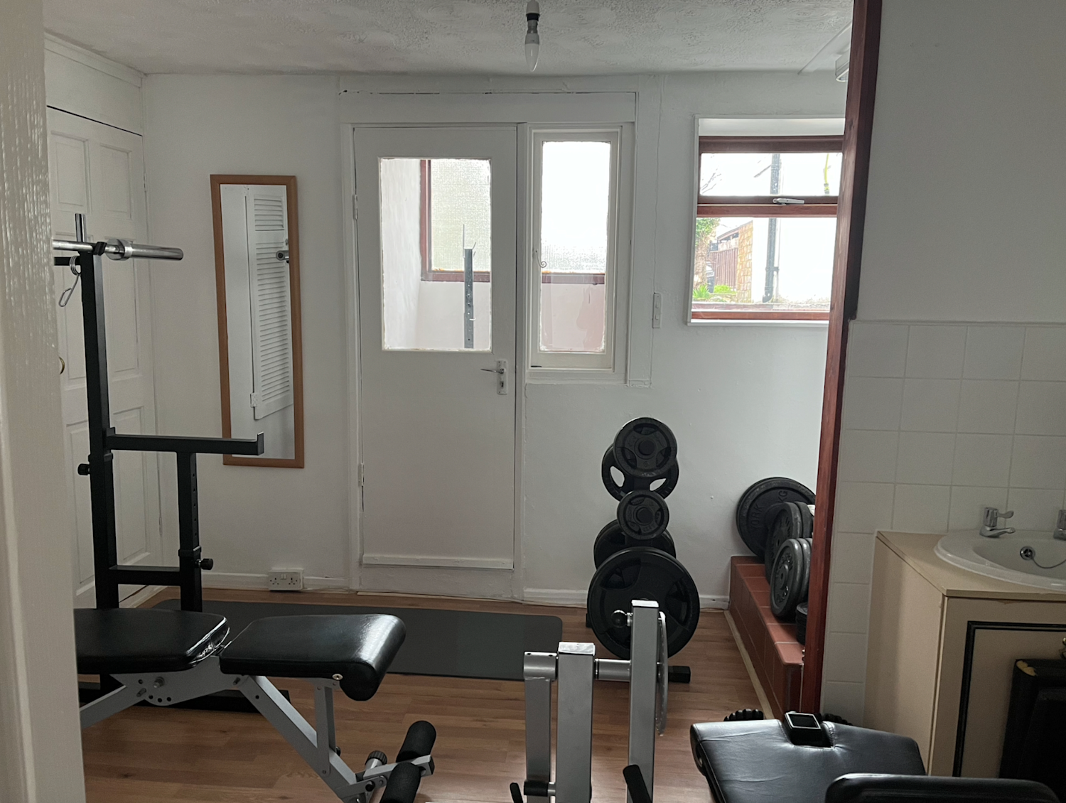 A basement annexe with its own doorway and facilities, currently being used as a gym and storage area