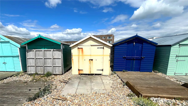 Row of beach huts, all painted different colours, in Lancing