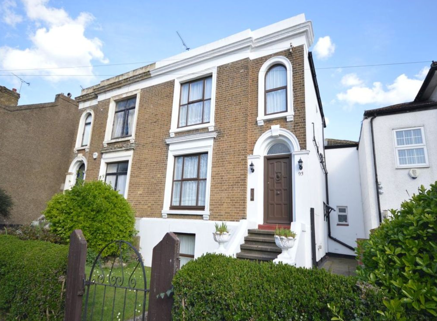 Large pale brick Georgian house with white stucco frontage and steps leading to the front door