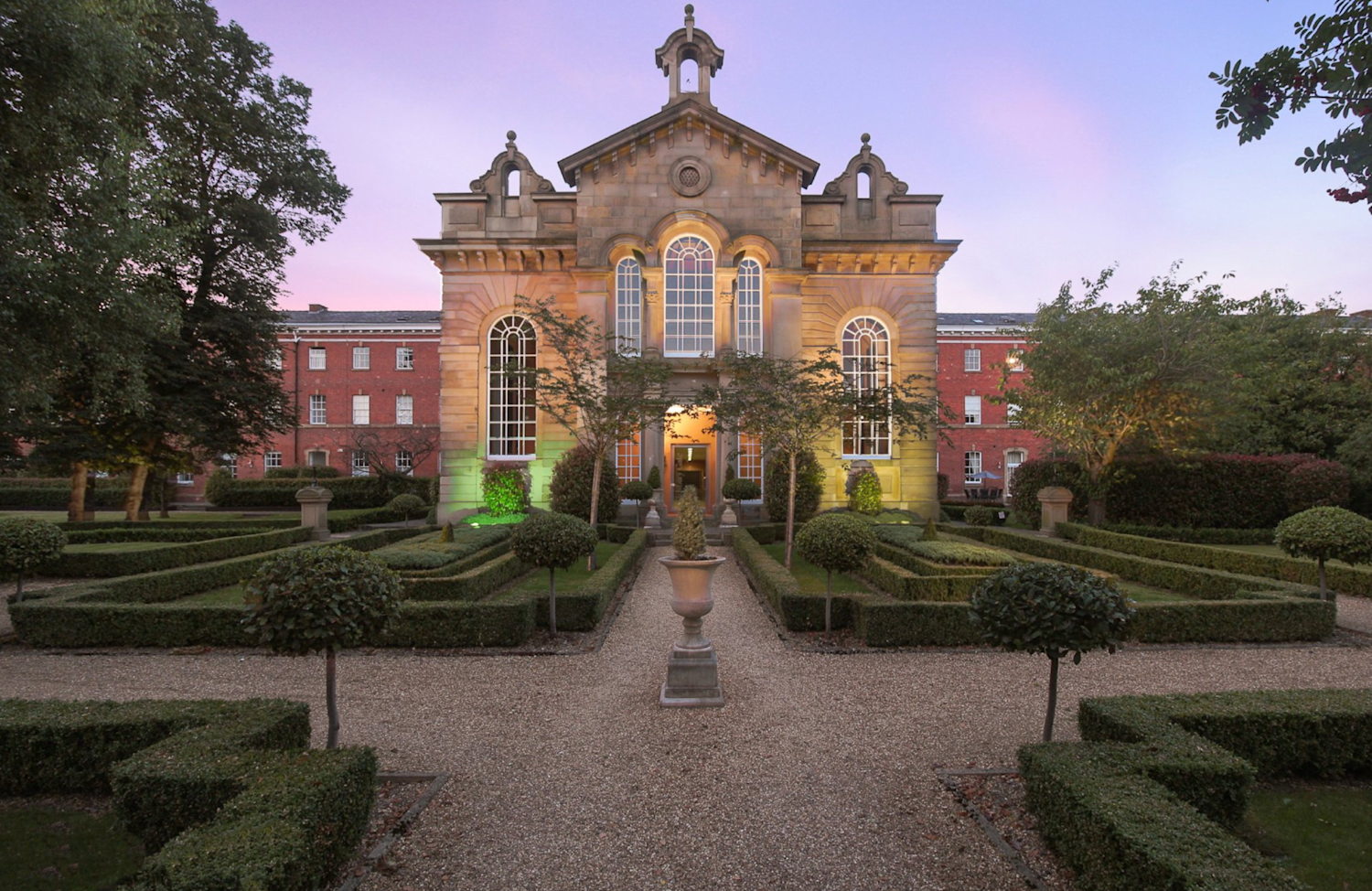 An impressive Georgian-era building with manicured and box hedged surrounding ornamental gardens