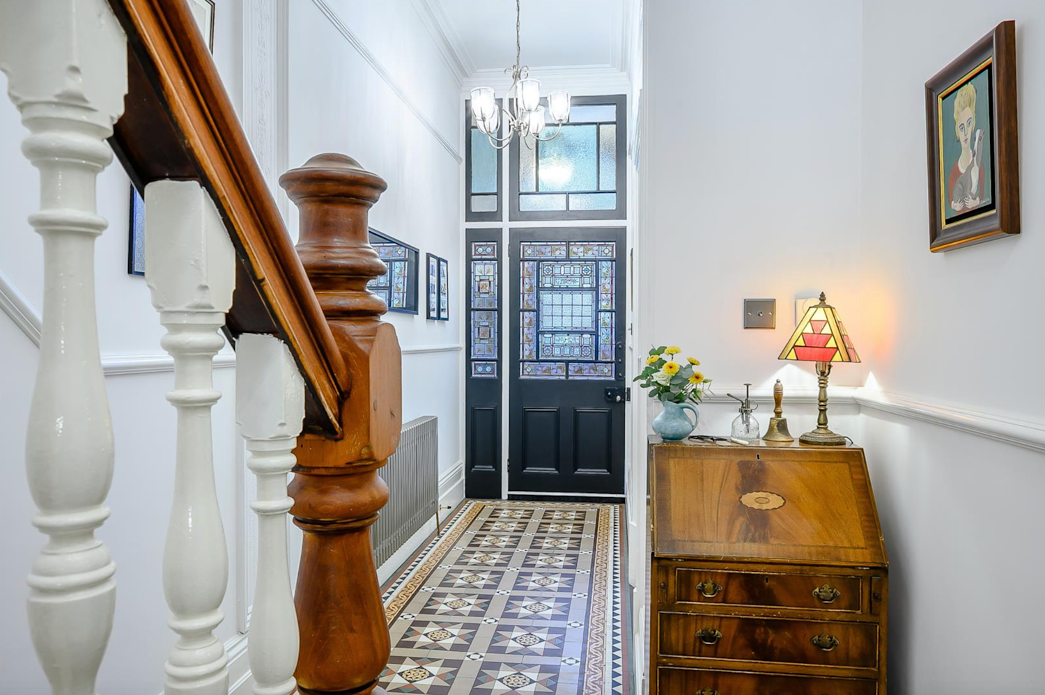 Interior of a Victorian property with period-style floor tiles, original stairway and bannisters