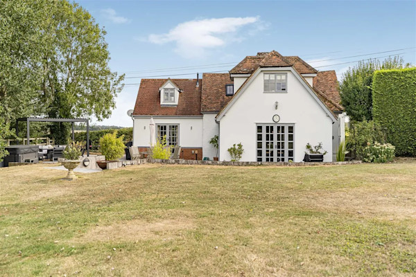The exterior of a white house with a large lawned garden