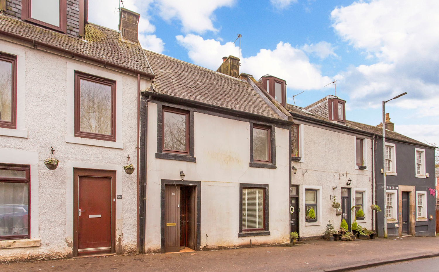 White terraced country cottages with white render and on-street parking
