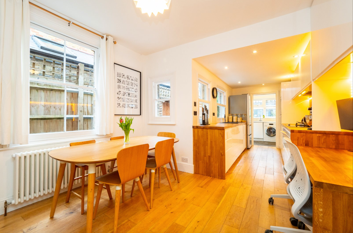 Interior of a stylish and modernised Edwardian terraced home, with pale wood floors, fitted kitchen and dining table