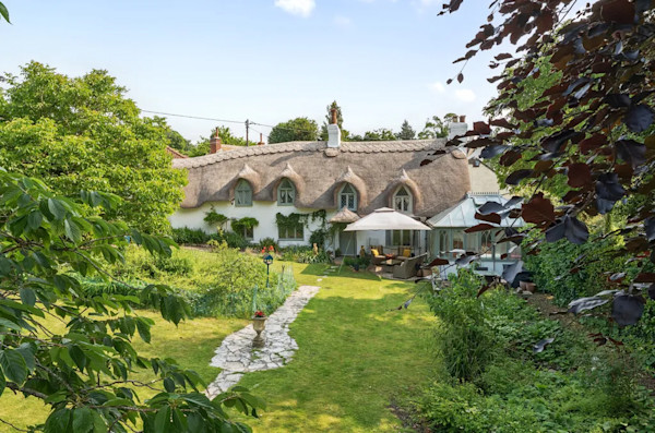 The exterior of a thatched cottage in a rural setting