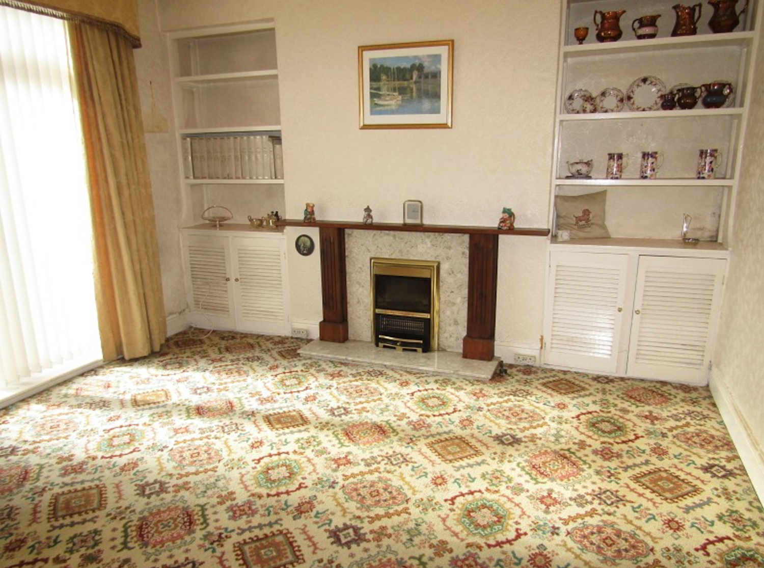Living room with fitted bookshelves and an old fashioned carpet