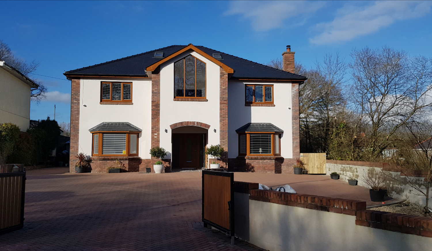 Modern detached house with a large driveway and a mixture of red brick and white render on the facade