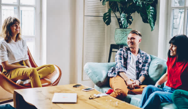Group of friends in a living room looking happy - Zoopla