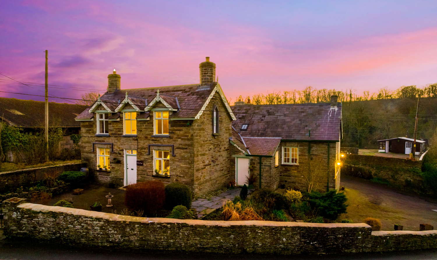 Period stone cottage in Wales, with surrounding countryside and a stunning pink sunset