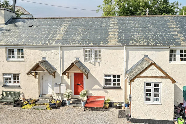 Aerial view of a row of pretty terraced cottages in cream washes and with pitched roofs over the front doors