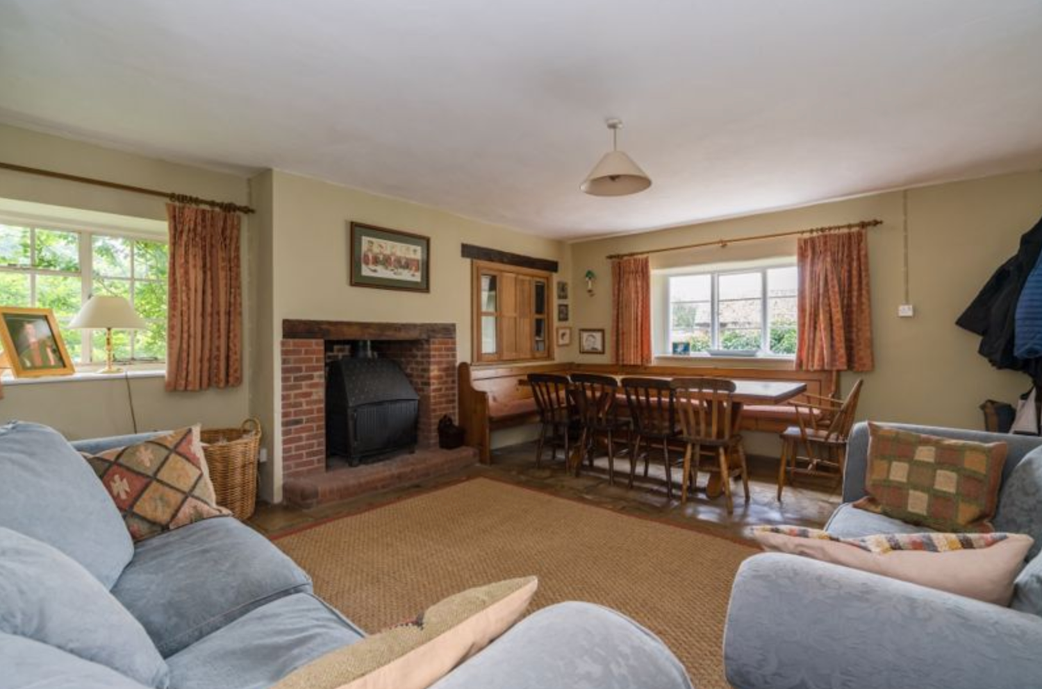 Sofas and dining area inside a large country house in Oxfordshire, with a cosy feel and slightly dated furniture
