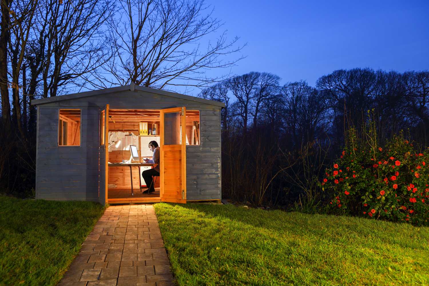 A man working in his office in the garden during the evening