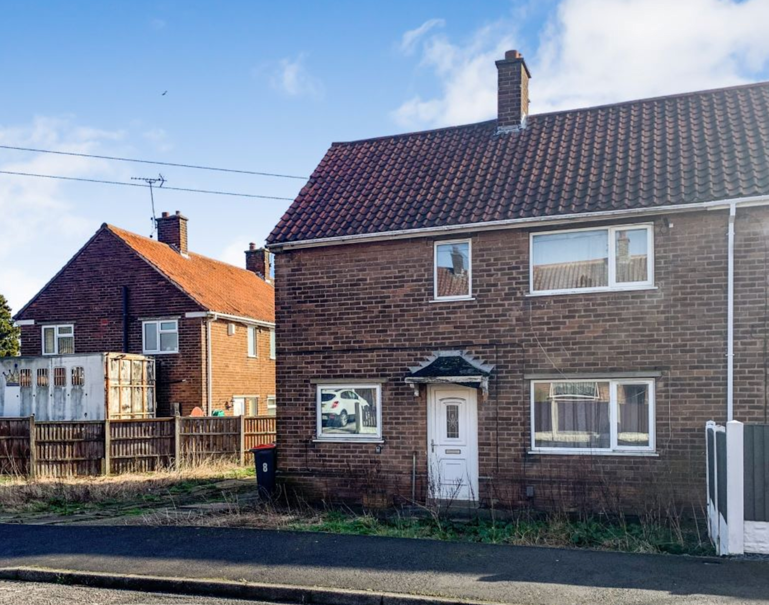 Semi-detached 1960s brick house with a small front garden and driveway to one side