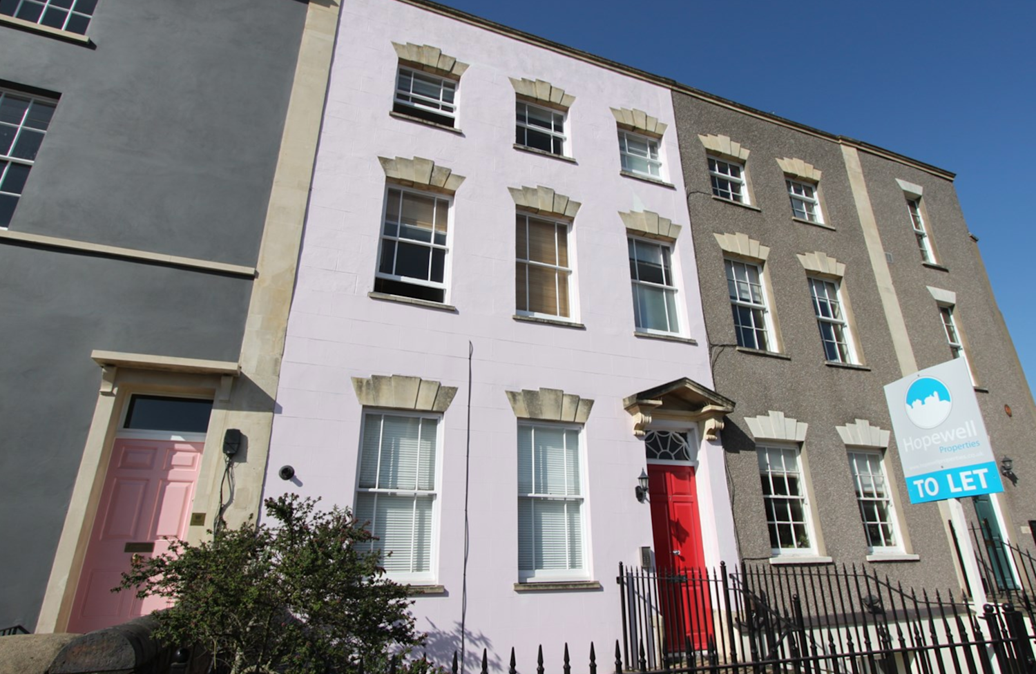 Bristol terraced townhouse with a bright red front door, pale pink exterior paintwork and Georgian style windows