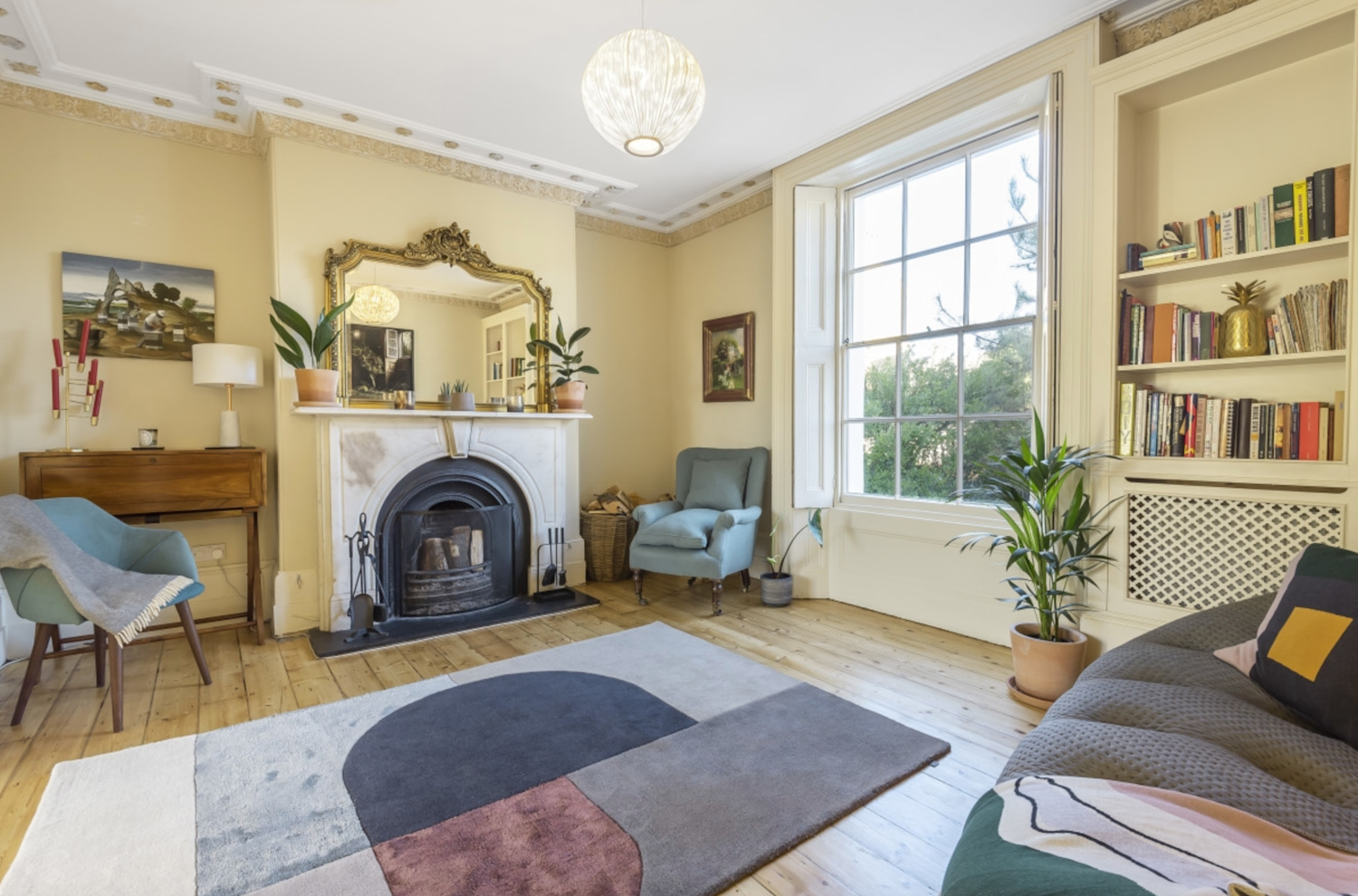 A Georgian living room with original fireplace, cornices and windows, with a modern interior and furniture