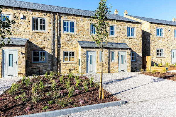 Collection of newly-built houses with flower beds and parking spaces in front