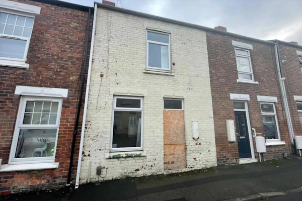 Cream-coloured house with front door boarded up