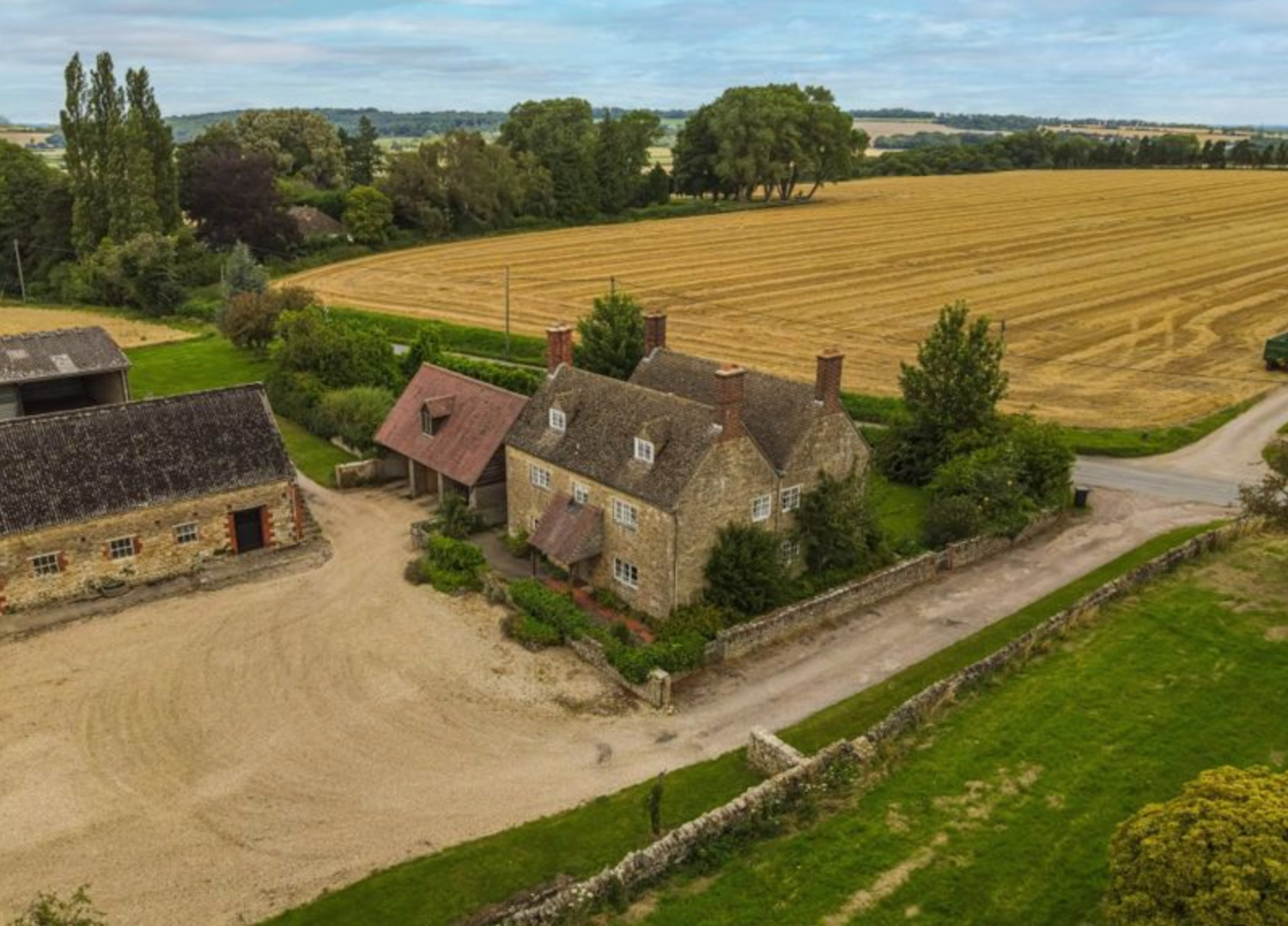 Beautiful old stone farmhouse with outbuildings and surrounding fields of wheat
