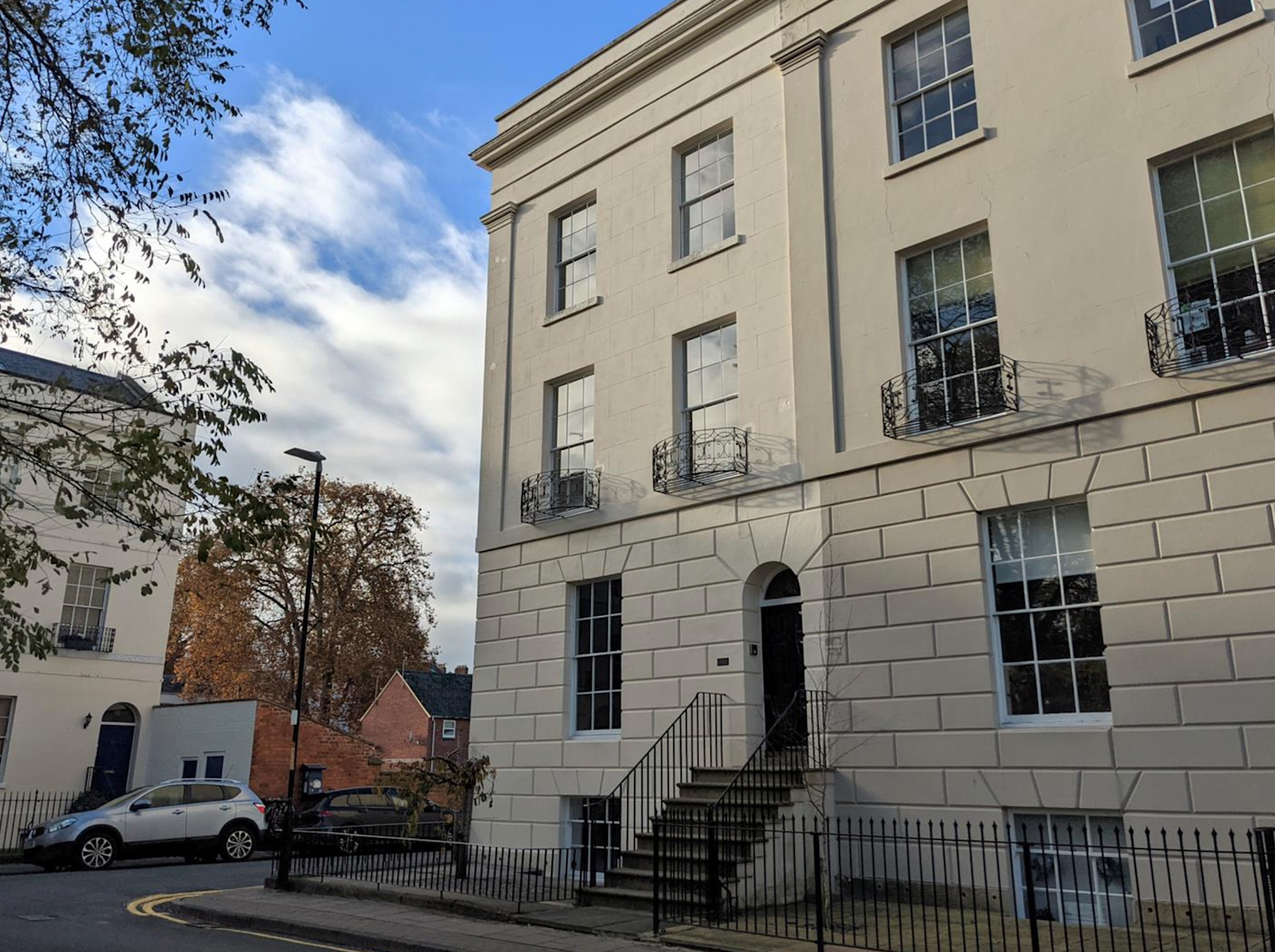 Exterior of a white Georgian townhouse with steps leading up to the front door
