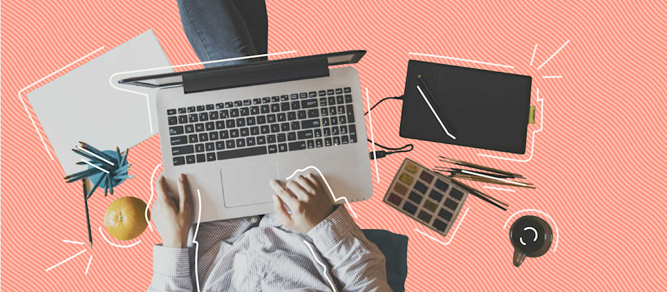 multi-tasking person with computer, tablet, pens and pencils on pink striped background