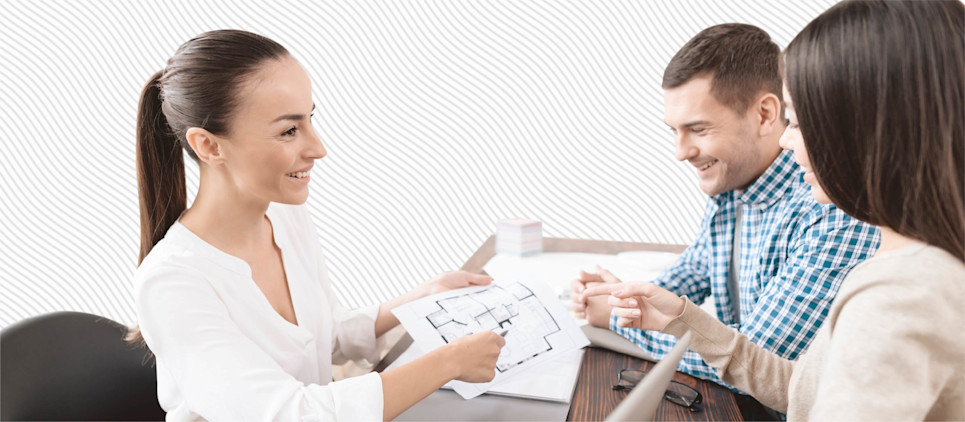 A couple and a real estate agent look at a floor plan.