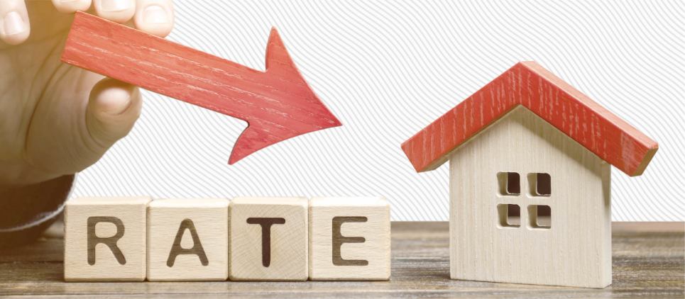 A hand holds a red arrow pointing downwards over a figurine of a house and block letters that read "rate".
