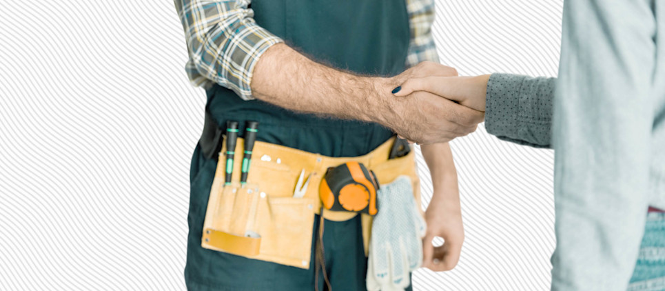 Person with a tool belt shakes another person's hand.