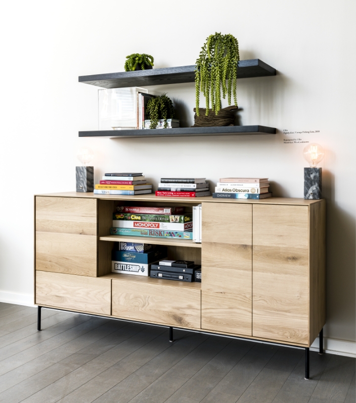 A trendy storage cabinet with boardgames and books in it.