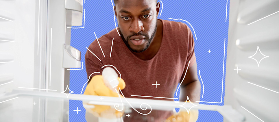 Man wearing gloves cleans the inside of a fridge with spray bottle.