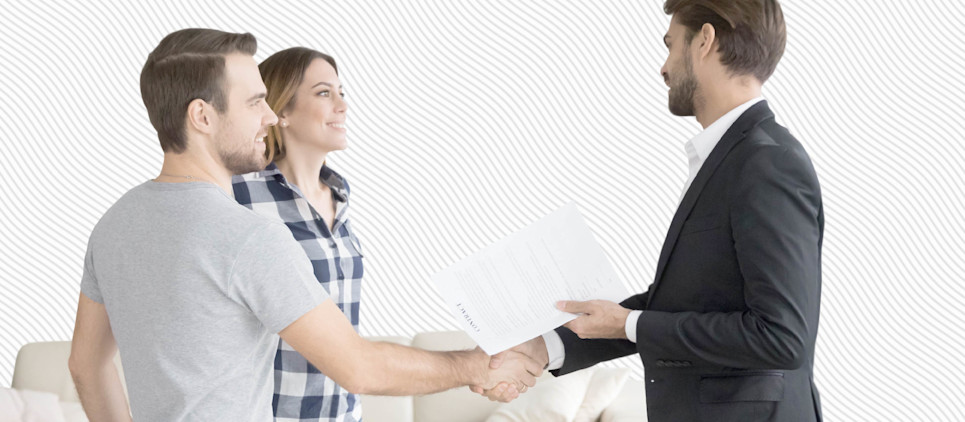 A couple shakes hands with a man in a suit.
