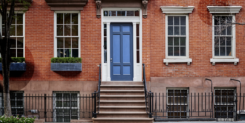 A brick building with a bright blue apartment door