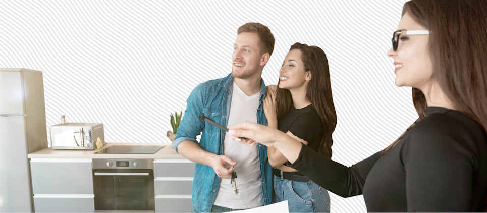A landlord holding a pen shows two new renters holding keys their new apartment.