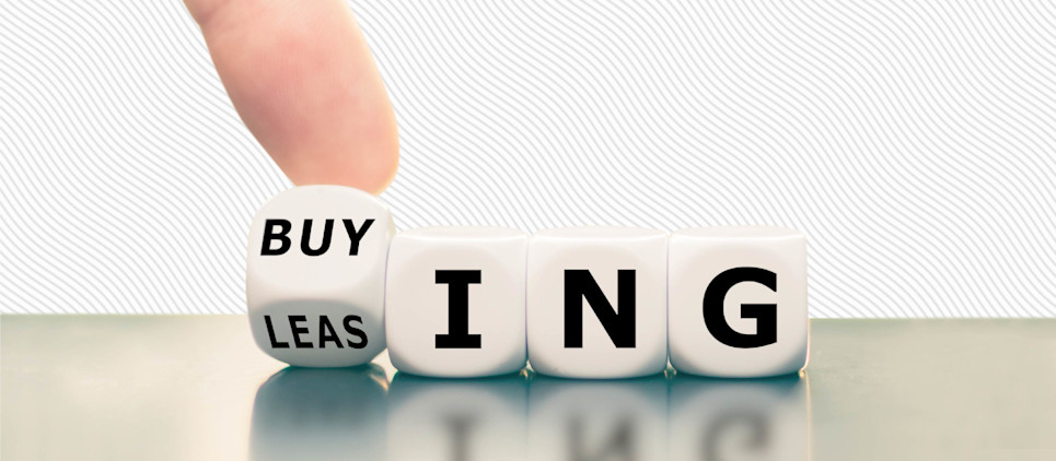 A finger turns over a die reading "buy" on one edge and "leas" on the other, the remaining four dice read "ing".