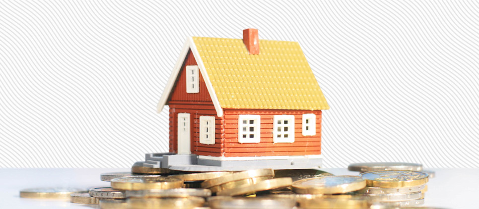 Small house figurine sits atop a pile of coins.