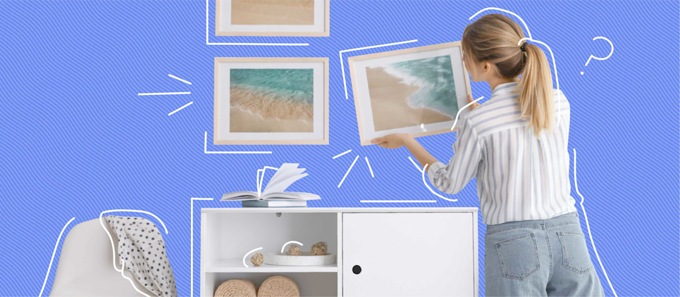 woman hanging multiple framed pictures