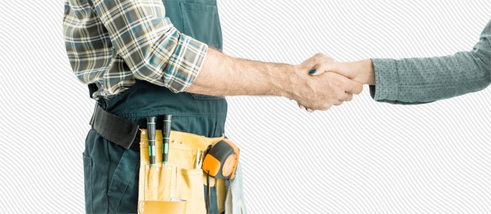 Person with a tool belt shakes another person's hand. 