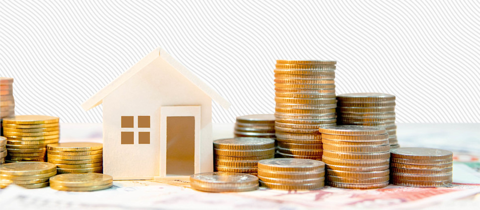 Miniature model house sits in-between stacks of coins.