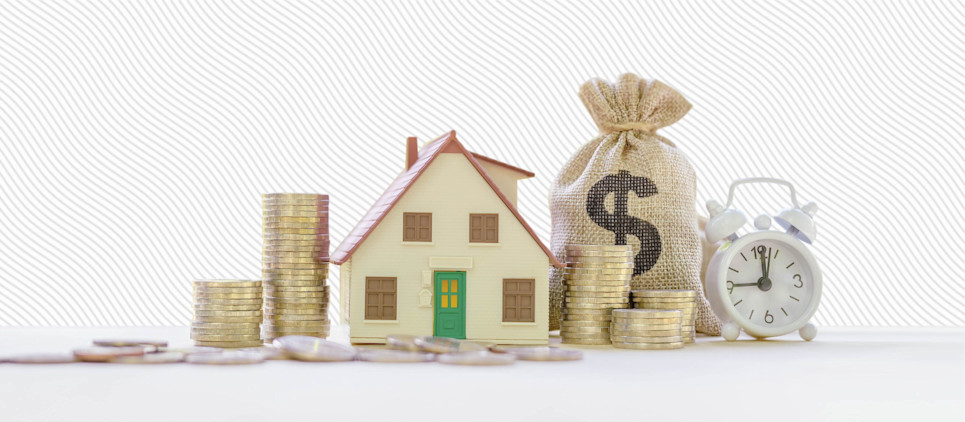 Small model house sitting on cash, surrounded by coin stacks, a clock and bag of coins. 