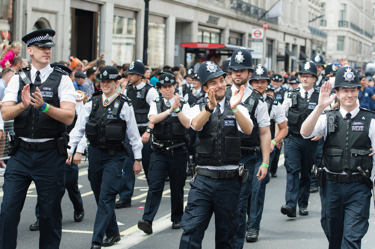 Police force marching and waving during pride parade