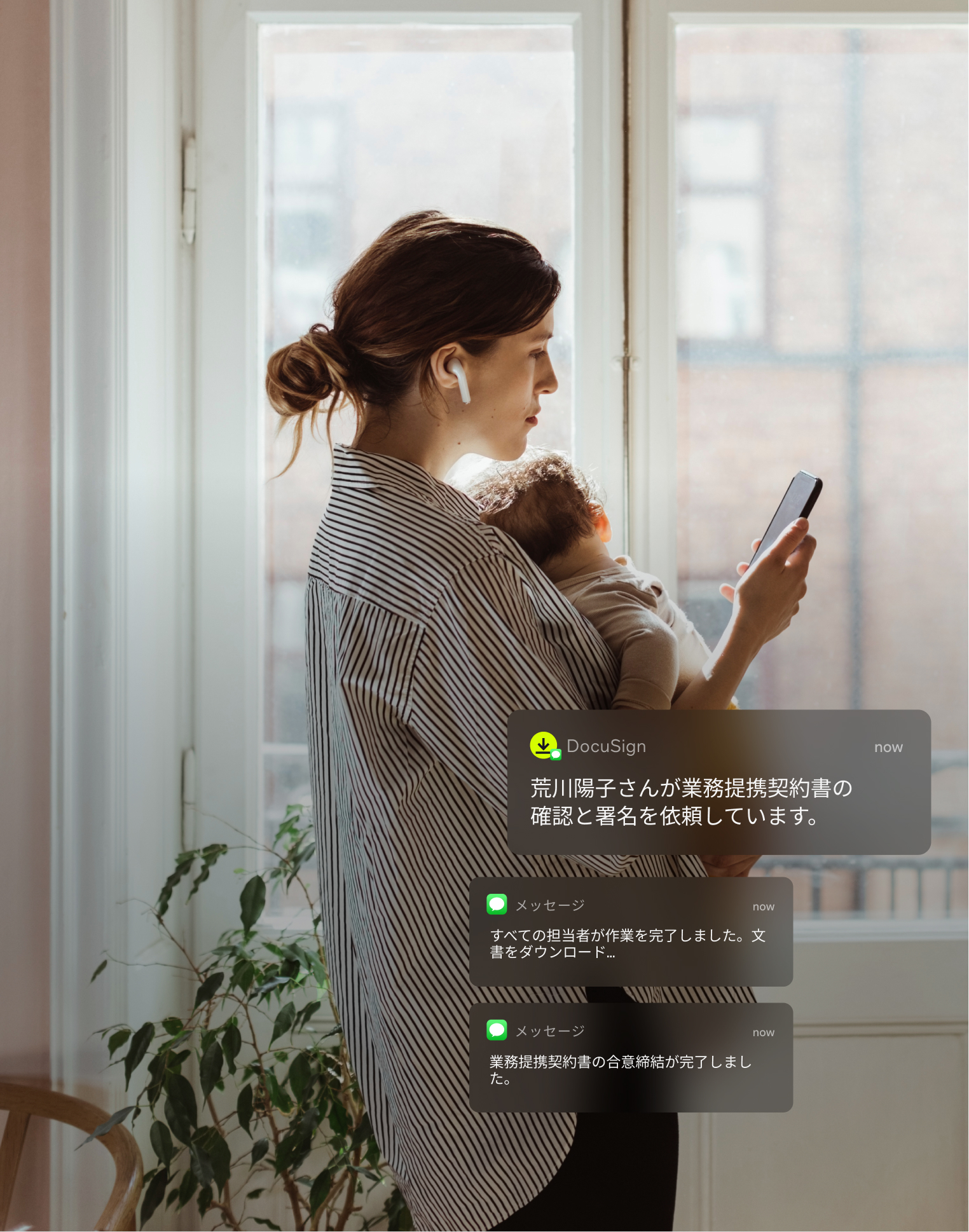 自宅で仕事をする母親がSMSで配信された署名済みの文書をモバイル端末で確認している様子。