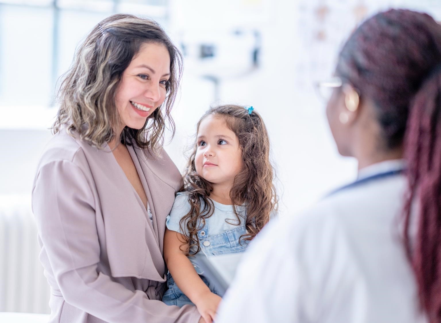 Photo of a mother and young daughter in a clinic talking with a physician.