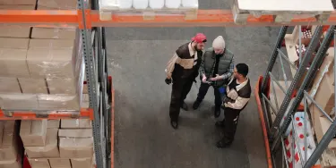 Drie mannen die in een warehouse werken, staan gebogen over een tablet samen.
