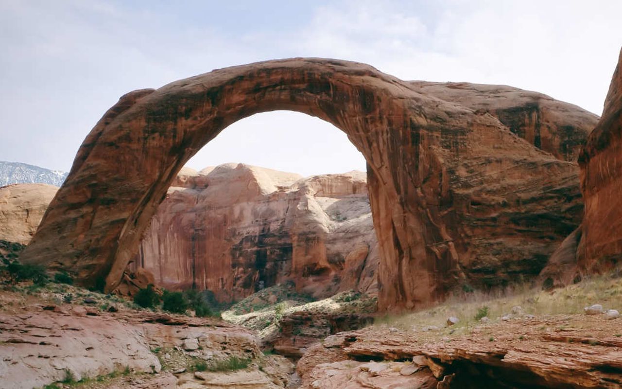 Rainbow Bridge | Photo Gallery | 1 -  Rainbow Bridge, on the edge of Lake Powell, is the largest natural bridge in the world at 290 feet/88 meters tall and 270 feet/83 meters across. Rainbow Bridge is considered sacred by the Navajo culture as a symbol of deities responsible for creating clouds, rainbows and rain - the essence of life in the desert.